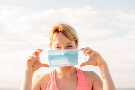 portrait of a beautiful blonde woman with a protective mask with the sky in the background, concept...