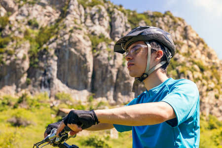 portrait of a young cyclist wearing a helmet, concept of sport and healthy lifestyle in nature, copy...