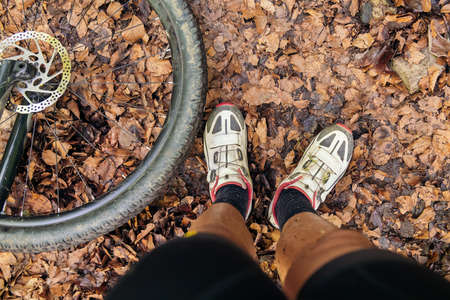 detail of a cyclist dirty legs and the wheel of his mountain bike, concept of effort in sport and...