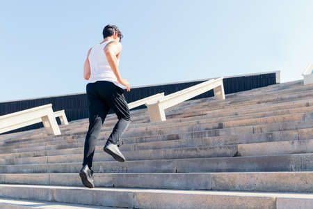 back view of a sportsman climbing a staircase during his training, urban sport concept and healthy lifestyle, copy space for textの写真素材