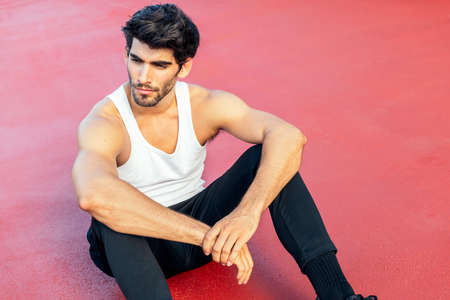 handsome sportsman rest sitting on a red floor, concept of urban sport and healthy lifestyle, copy...