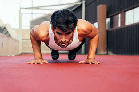 handsome sportsman doing push ups on a red floor, concept of urban sport and healthy lifestyle, copy...
