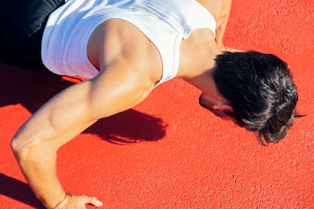 close-up of an unrecognizable sportsman doing push-ups on a red floor, concept of urban sport and...