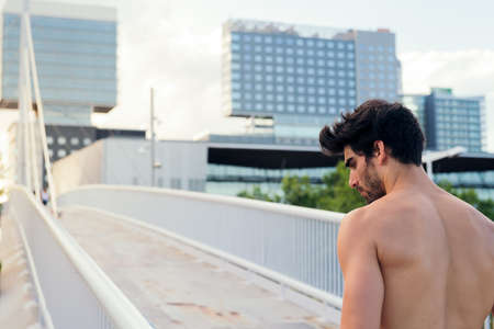 shirtless athlete concentrating next to a city bridge in front of buildings, urban sport and healthy lifestyle concept, copy space for textの写真素材