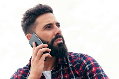 portrait of a handsome bearded man talking by mobile phone, concept of freedom and technology, copy space for textの写真素材