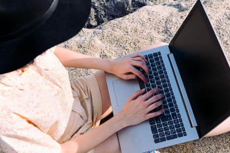 top view of the hands of an unrecognizable young traveler woman typing in a computer outdoors, concept of digital nomad and blogger lifestyleの写真素材