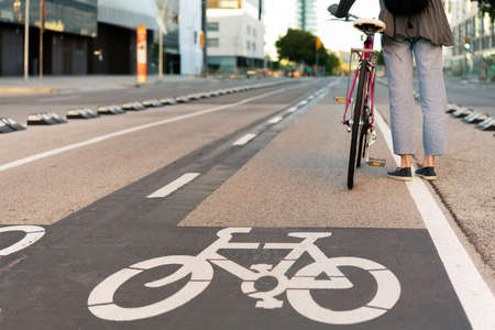 rear view of the legs of an unrecognizable young woman standing by the bike path with a pink retro style bicycle, concept of active lifestyle and sustainable mobilityの写真素材