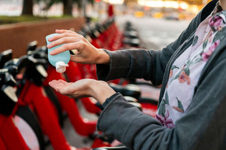 hands washing with disinfectant gel next to an urban bicycle rental parking, concept of protection...