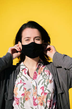 vertical portrait of a young girl wearing protective mask with a yellow background, concept of...