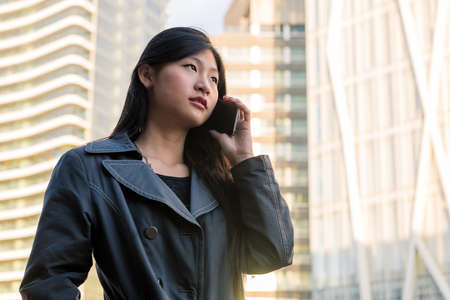 classy young asian woman talking on mobile phone in the city, technology and urban lifestyle concept, copy space for textの写真素材
