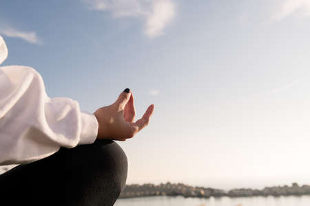 detail of the hand of a woman meditating by the sea, relaxation and mental health concept, copyspace...