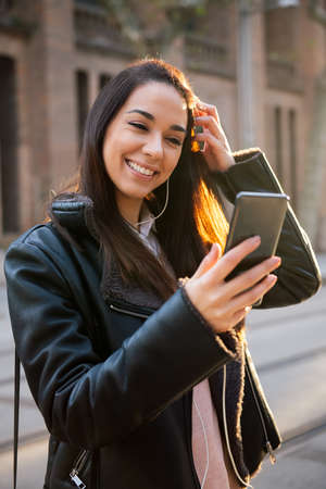 vertical photo of a happy young woman smiling while reading a message at her telephone at the...