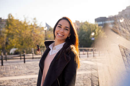 happy young woman smiling and walking down a cobblestone street, concept of happiness and urban...