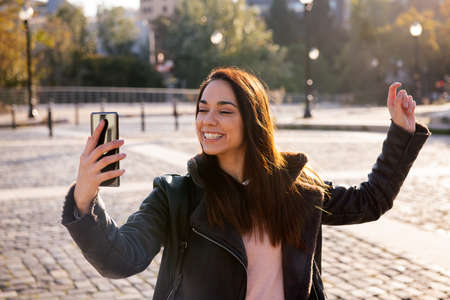 happy young woman smiling and celebrating looking the phone on a cobblestone street, concept of...