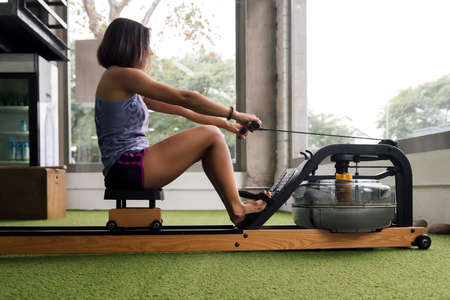 sportswoman training his strength in the gym with a water rowing machine, active and sporty lifestyle conceptの写真素材
