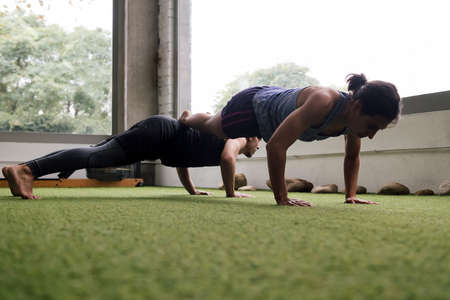 sportsman and sportswoman training together in the gym doing push-ups, active and sporty lifestyle...