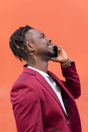 vertical profile portrait of a stylish african businessman in suit laughing and talking on phone in...