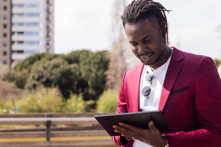 african businessman using a tablet outdoors in the city, technology and remote work concept, copy space for textの写真素材