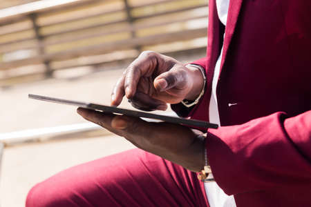 detail of the hands of a black man using a tablet outdoors in the city, technology and remote work conceptの写真素材