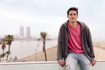 attractive young student sitting in front of the city, concept of youth and urban life style, copy space for textの写真素材