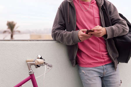 unrecognizable young man with his bicycle using phone, concept of technology and urban lifestyle,...