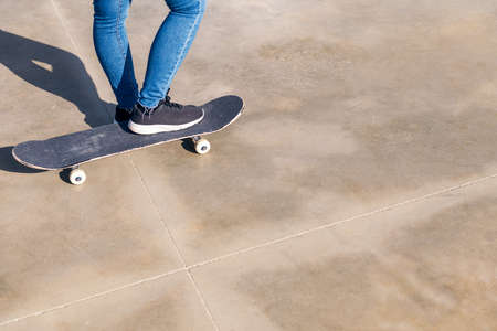 skateboard and feet of an unrecognizable person on a concrete floorの写真素材
