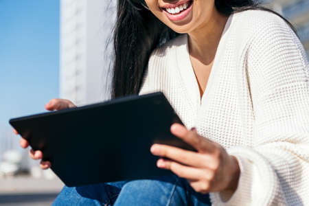 unrecognizable young woman using tablet outdoors, focus on the womanの写真素材
