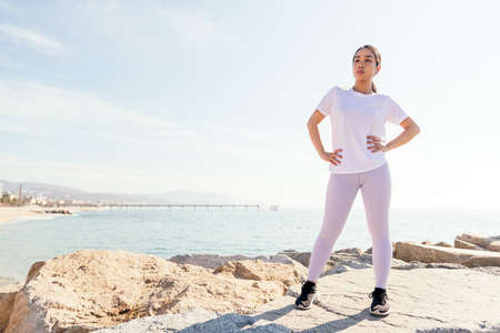 young asian sports woman standing taking a break during her outdoor training session, concept of sport and active lifestyleの写真素材