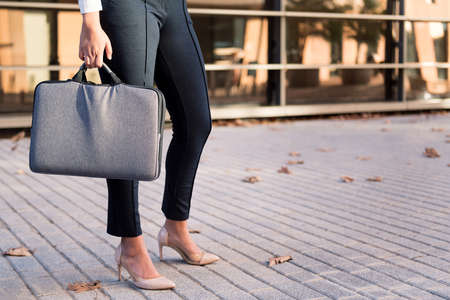 legs of a businesswoman with heels and briefcase in front of an office building in the financial district, concept of successful entrepreneur and urban lifestyle, copy space for textの写真素材