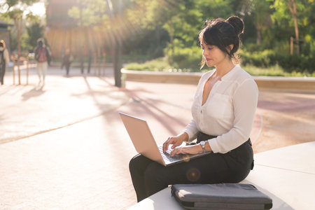businesswoman working with her laptop computer in a park in the financial district at dawn, concept of digital entrepreneur and urban lifestyle, copy space for textの写真素材