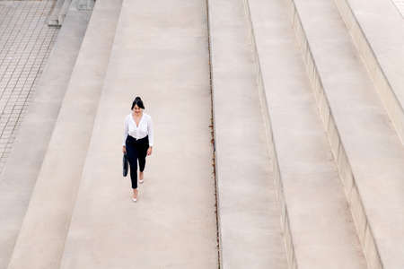 top view of a businesswoman walking with a briefcase on a concrete floor, concept of successful entrepreneur and urban lifestyle, copy space for textの写真素材