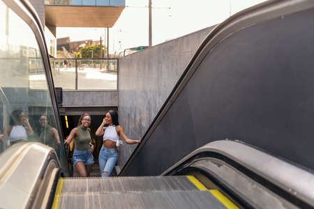 two black girls going up the escalator in the subway, concept of friendship and urban lifestyle