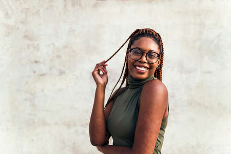 young african girl with glasses smiles happy with a gray concrete wall in the background, concept of youth and racial diversity, copy space for textの写真素材