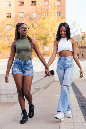 young black female couple strolling holding hands, concept of love and diversityの写真素材