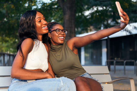 two young black women smiling happily while taking a selfie photo with the mobile phone, concept of...