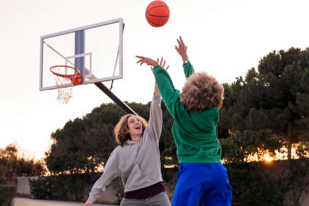 couple of young friends playing basketball outdoors on a city court, concept of urban sport in the streetの写真素材