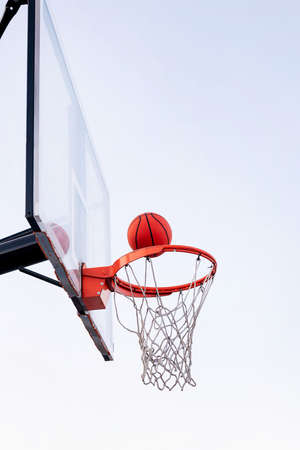 ball entering in a basketball hoop with the sky in the background, concept of urban sport outdoors, copy space for textの写真素材