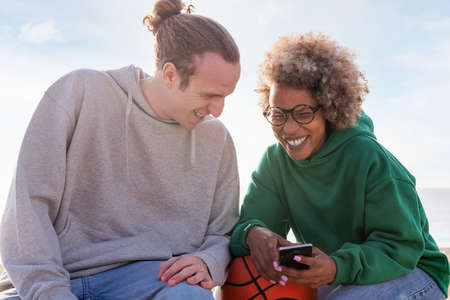couple of young friends laughing while looking at mobile phone, concept of lifestyle and technology...