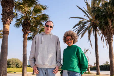 young caucasian man and latin woman smiling happy looking at camera next to palm trees, concept of...