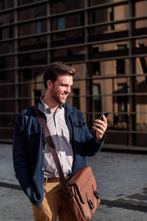 businessman looking phone by an office building