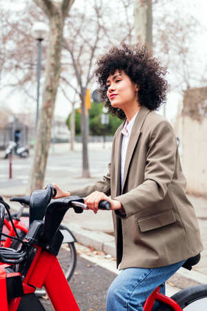 young latin woman rides a electric rental bikeの写真素材
