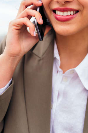 mouth of a smiling woman talking by mobile phone