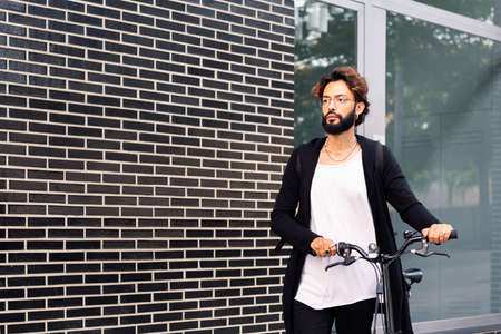 young caucasian man walking with his bike, concept of urban lifestyle and sustainable mobility, copy...
