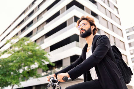 stylish young bearded man riding his bike through the city, concept of urban lifestyle and...