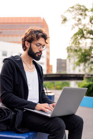 stylish young student working on his laptop computer at the university campus, concept of technology...