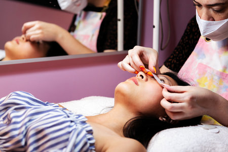 woman being prepared to have her eyelashes trimmed