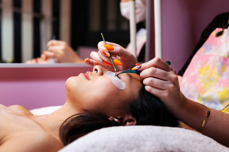 beautician applying false eyelashes to young womanの写真素材