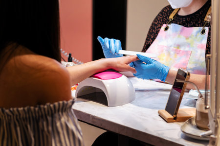 hands of a beautician filing nails during manicureの写真素材