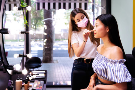 makeup artist applying make-up to a young womanの写真素材
