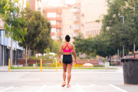 rear view of a female athlete walking on the cityの写真素材